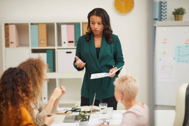 Çekici Afrikalı Amerikalı iş kadını toplantıda, meslektaşları el çırpıyor.