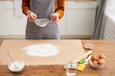 Mutfakta yemek pişirme dersi çekerken kabartma tozu seçen tanınmayan bir kadının yüksek açılı görüntüsü.