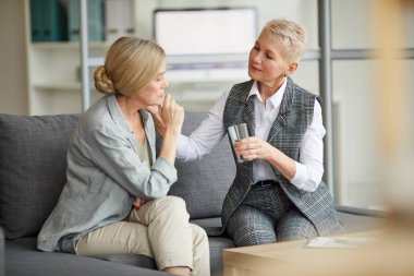 Terapi sırasında yaşlı kadına su sunan ilgili kadın psikoloğun portresi.