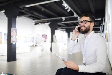 Müzedeki sergiye hazırlanırken telefonla konuşan sakallı sanat galerisi müdürünün portresi.