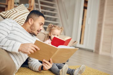 Küçük tatlı kızıyla kitap okuyan genç babanın portresi, kopyalama alanı.