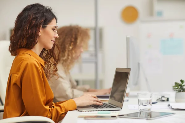 現代のオフィスでコンピュータに取り組んでいる2人の白人女性の横側のビューショット — ストック写真