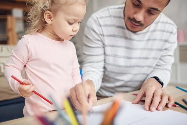 Cropped portrait of contemporary young dad drawing pictures with cute little daughter at home, copy space