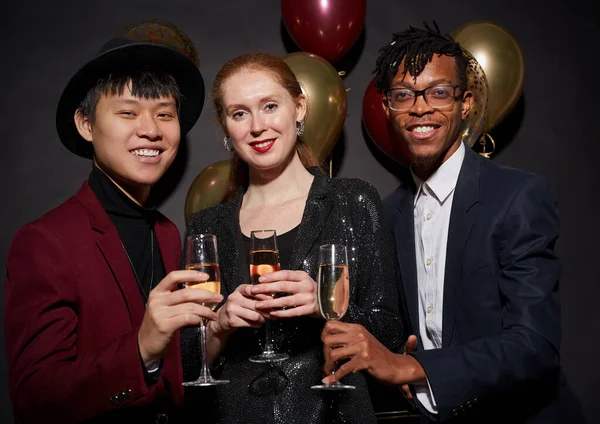 パーティーで黒を背景にポーズをとりながら シャンパングラスを手にしたエレガントな若者たちのグループは フラッシュで撮影 — ストック写真
