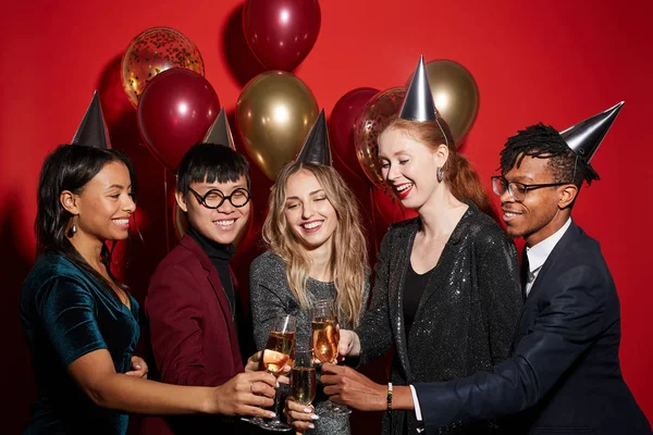 風船で赤を背景にパーティーを楽しみながらシャンパングラスをクリックする陽気な若者の多民族グループ コピースペース — ストック写真