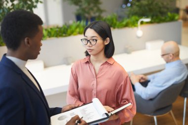 Genç Asyalı iş kadınının modern ofiste projeyi tartışırken partneriyle konuşması, kopyalama alanı