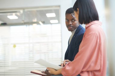 Başarılı Afrikalı iş adamının yan görünüş portresi ofis içi fotokopi çekerken kadın iş arkadaşı ya da sekreterle konuşuyor.