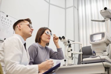 Modern oftalmoloji kliniğinde görüş testi sırasında genç bir optometristin yan görüş portresi, fotokopi alanı
