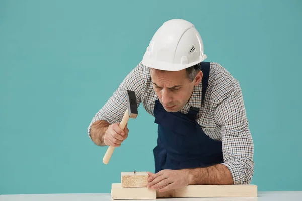 Retrato Carrancudo Trabalhador Sênior Martelando Unhas Enquanto Construção Estrutura Madeira — Fotografia de Stock