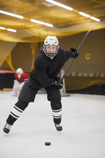 Full length portrait of female hockey player leading pluck during practice on ice, copy space