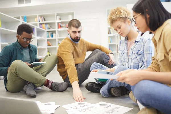 Pełne Spojrzenie Wieloetniczną Grupę Studentów Siedzących Piętrze Bibliotece Omawiających Projekt — Zdjęcie stockowe