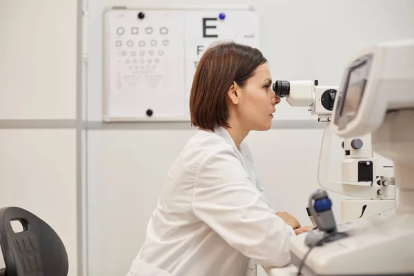 Zijaanzicht Portret Van Jonge Vrouwelijke Oogarts Met Behulp Van Refractometer — Stockfoto