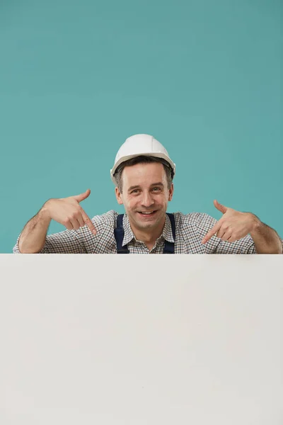 Retrato Trabalhador Sorrindo Usando Chapéu Duro Apontando Para Sinal Branco — Fotografia de Stock