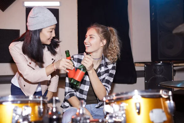 音楽スタジオでビールボトルをクリックしている2人の流行の若い女性の肖像画 フラッシュで撮影 — ストック写真