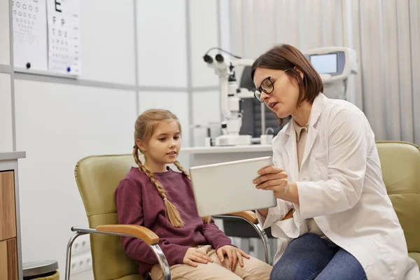 현대의 진료소에서 상담하는 디지털 태블릿을 사용하여 의사가 소녀에게 이야기하는 — 스톡 사진