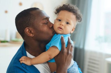 Mutlu Afro-Amerikan baba portresi. Evinde küçük sevimli bir çocuğu öpüyor. Kopya uzay.