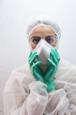 Virüs salgını sırasında koruyucu giysi, solunum maskesi ve gözlük takan genç bir kadının portresi