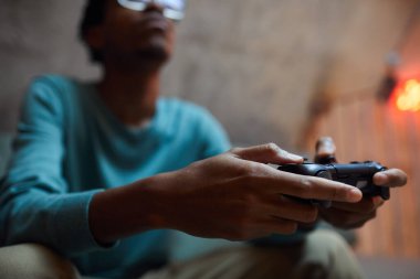 Video oyunları oynarken elinde oyun alanı denetleyicisi olan çağdaş Afro-Amerikalı adamı kapat