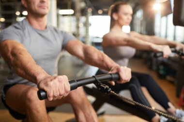 Modern spor salonunda egzersiz makinesini kullanan kaslı bir adamın kesilmiş görüntüsü, boşluğu kopyala