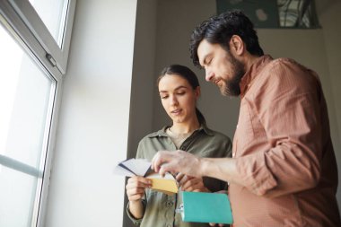 Evi yeniden dekore ederken, renk örneklerine bakan mutlu çiftin düşük açılı portresi, boşluğu kopyala