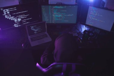 Karanlık odada programlama kodu üzerinde çalışırken, tanımlanamayan siber güvenlik hackerının üst görüntüsü, boşluğu kopyala
