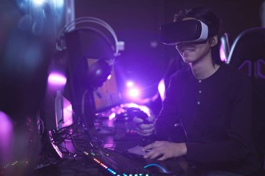 Siyah siber iç mekanlarda yarış vardiyası kullanarak video oyunu oynarken VR kulaklık takan Asyalı genç bir adamın yan görünüm portresi, boşluğu kopyala