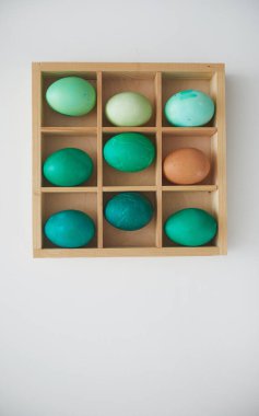 Elle boyanmış zümrüt Paskalya yumurtalarının beyaz arka planda minimum kompozisyonda düzenlenmiş ahşap sandıkta üst görüntüsü, kopyalama alanı