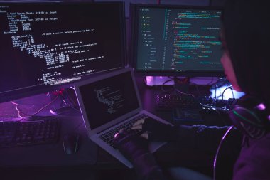 Karanlık odadaki çoklu ekran programlama ya da güvenliği kırma ile çevrili tanınmayan genç adam, boşluğu kopyala