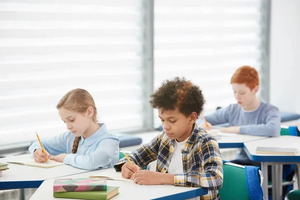 Multi Etnikai Csoport Gyerekek Ülnek Asztaloknál Iskolában Írás Vagy Tesztelés — Stock Fotó
