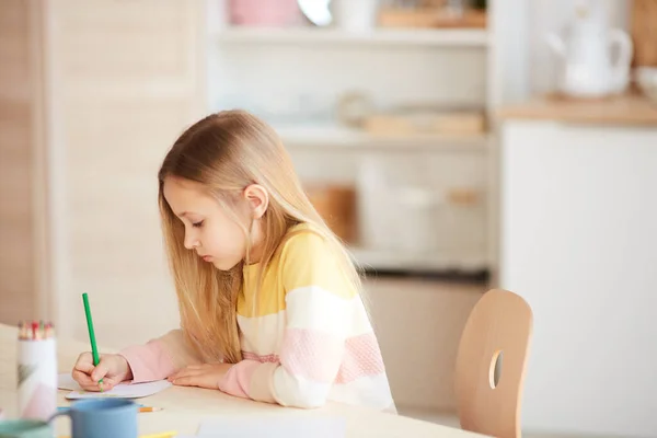 可爱小女孩坐在家中餐桌边画画或做作业时的侧视图肖像 复制空间 — 图库照片