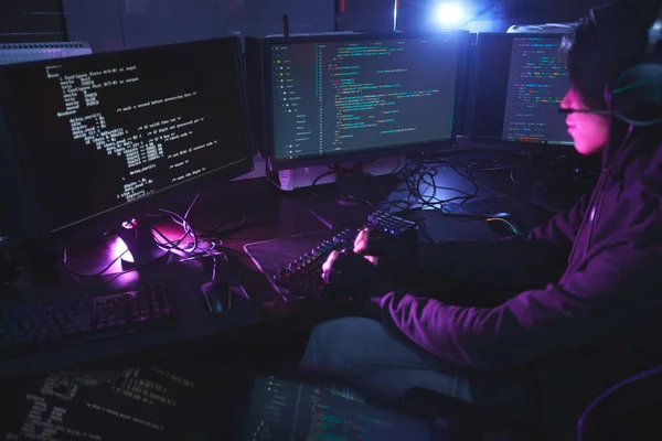 暗い部屋で複数のスクリーンプログラミングやハッキングセキュリティに囲まれた若い男の広い角度ビュー コピースペース — ストック写真
