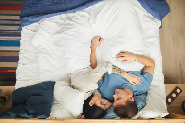青とカバーしながら快適なベッドの上で一緒に寝ている現代の若いカップルのトップビューの肖像画 スペースをコピー — ストック写真