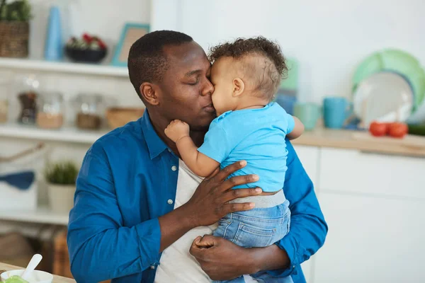幸せなアフリカ系アメリカ人のお父さん接吻小さな男の子ホワイト座ってキッチンテーブル コピースペース — ストック写真