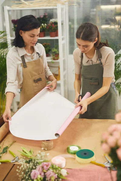 Retrato Vertical Dos Mujeres Jóvenes Desenrollando Papel Regalo Mientras Decoran — Foto de Stock