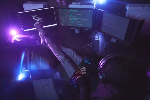 暗い部屋で複数のスクリーンプログラミングやハッキングセキュリティに囲まれた若い男のトップビュー コピースペース — ストック写真
