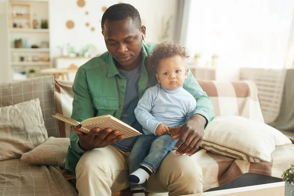 成熟したアフリカ系アメリカ人男性の肖像父親の膝の上に座って子供に本を読んで スペースをコピー — ストック写真