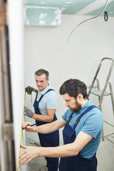 Högvinkelporträtt Två Byggnadsarbetare Som Mäter Vägg Vid Renovering Hus Kopiera — Stockfoto