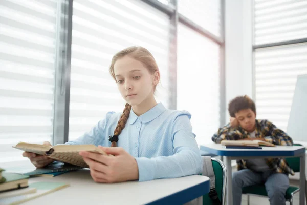 Porträtt Blond Intelligent Flicka Läsa Bok När Sitter Vid Skrivbordet — Stockfoto