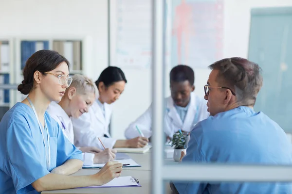 Porträtt Ung Kvinnlig Läkare Talar Med Kollega Sittande Vid Bordet — Stockfoto