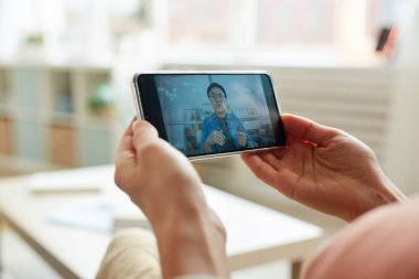 Tanımlanamayan kişi Asyalı adamın konuşmasını izliyor. Akıllı telefondan, yatay yakın plan çekimde.