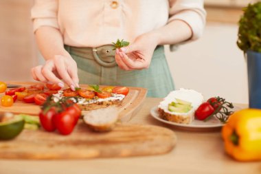 Sıcak tonda, tanınmayan bir kadının, sıcacık mutfağın içinde kahvaltıya sağlıklı domatesli sandviç hazırlaması, fotokopi çekmesi.