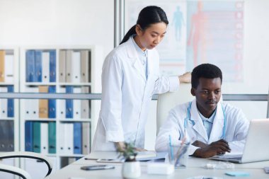 Tıp fakültesinde ya da stajda dizüstü bilgisayar kullanan iki genç doktorun portresi.