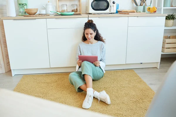 Mujer Joven Sentada Suelo Sala Cocina Viendo Videos Tableta Rosa — Foto de Stock