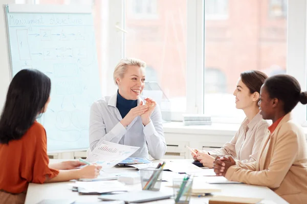 Grupo Mujeres Negocios Alegres Compartiendo Ideas Mientras Sientan Mesa Contra —  Fotos de Stock