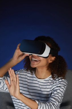 Sanal gerçeklik teçhizatı takan genç Afro-Amerikalı kadının dikey portresi.
