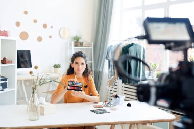 Kafkas güzellik blogcusu odasında oturmuş kamerada yeni ruj paletini gösteriyor.