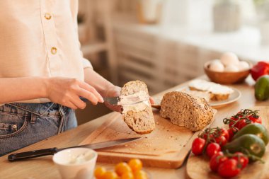 Sıcak tonda, tanınmayan bir kadının, sıcak mutfakta kahvaltı hazırlarken sandviç hazırlaması, uzay fotokopisi çekmesi.
