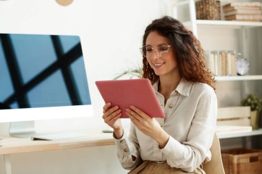 İş için tablet bilgisayar kullanan gözlüklü genç bir iş kadınının yatay portresi.