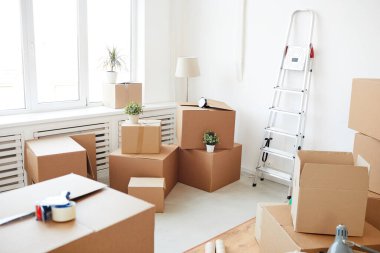 Wide angle background of stacked cardboard boxes in empty white room, moving, relocation and house decor concept, copy space clipart