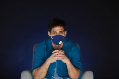 Karantinada film izlerken maske takan sakallı bir adamın portresi.